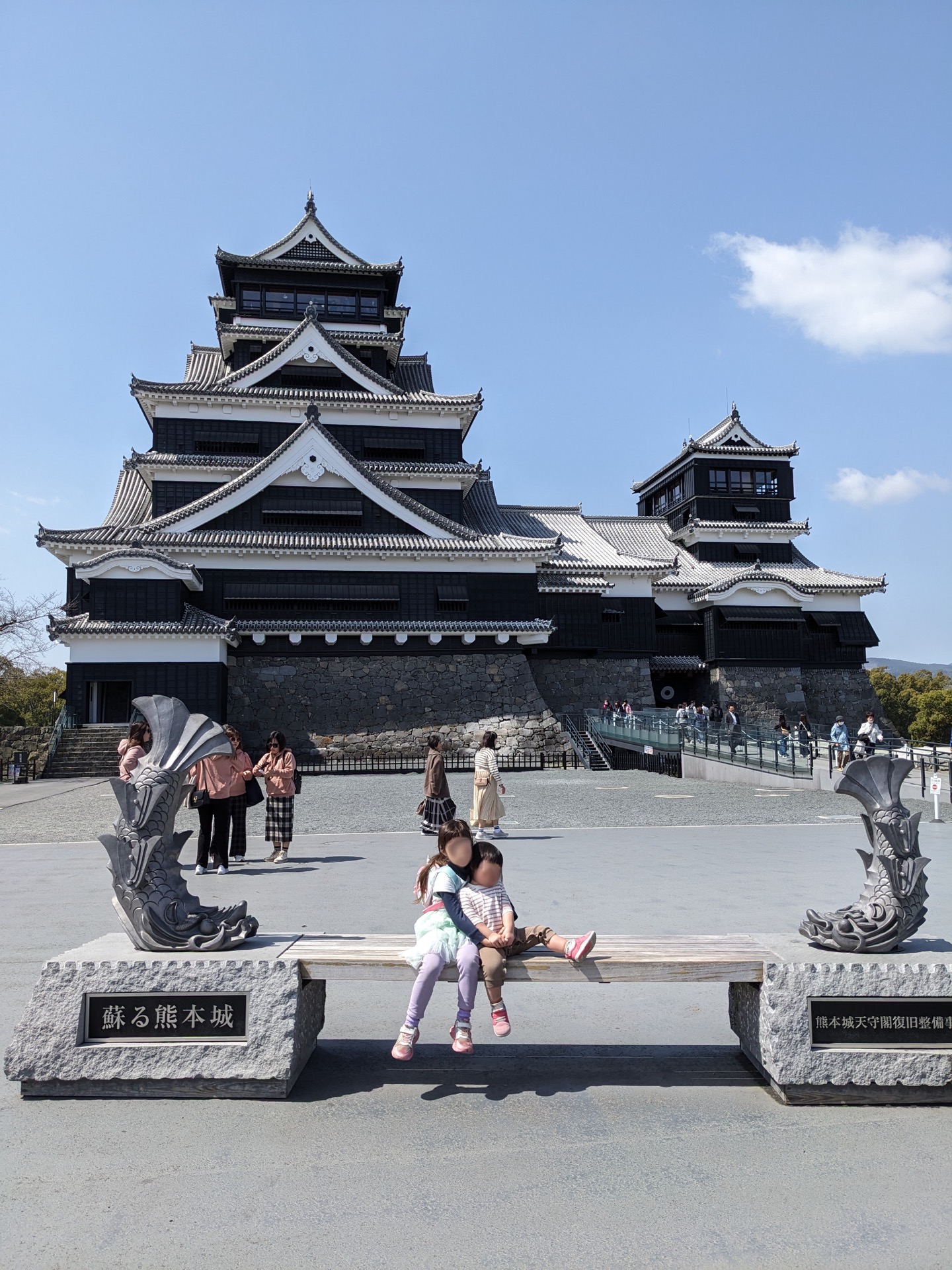 Kumamoto Castle and surrounding stone courtyard with vistors walking around